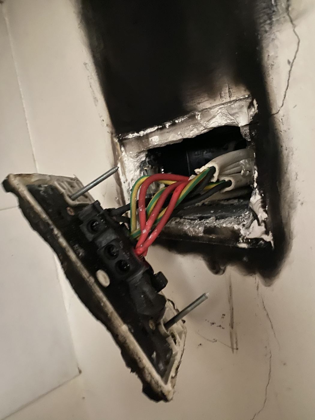 Burnt power point pulled from a wall with heavy soot damage around the wall box