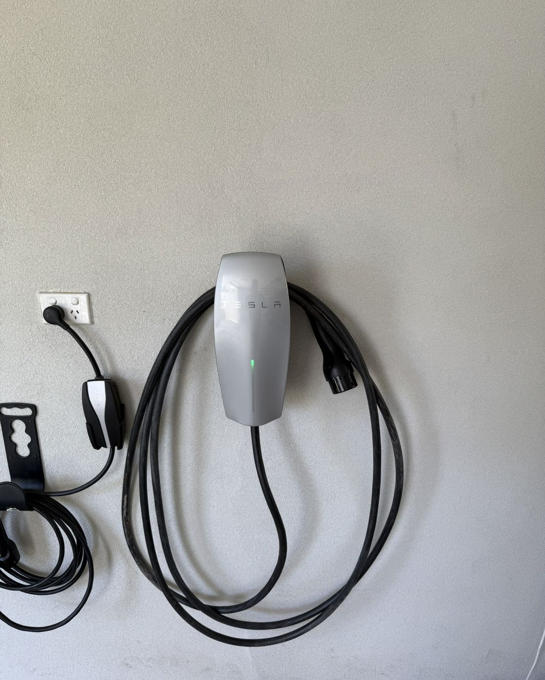 Tesla Wall Connector installed in a garage next to a portable charger