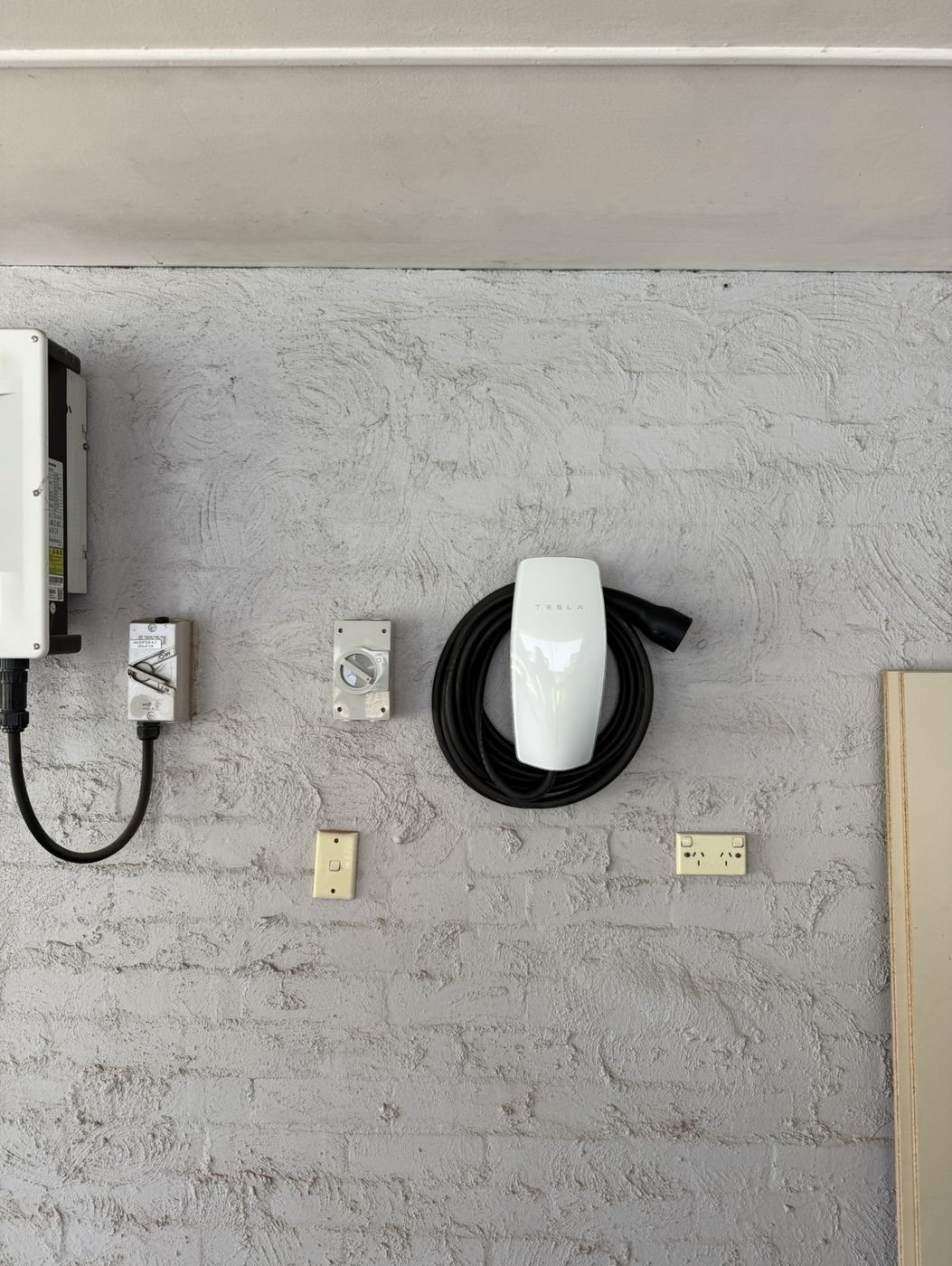 Tesla Wall Connector with isolator next to a solar inverter on a rendered wall