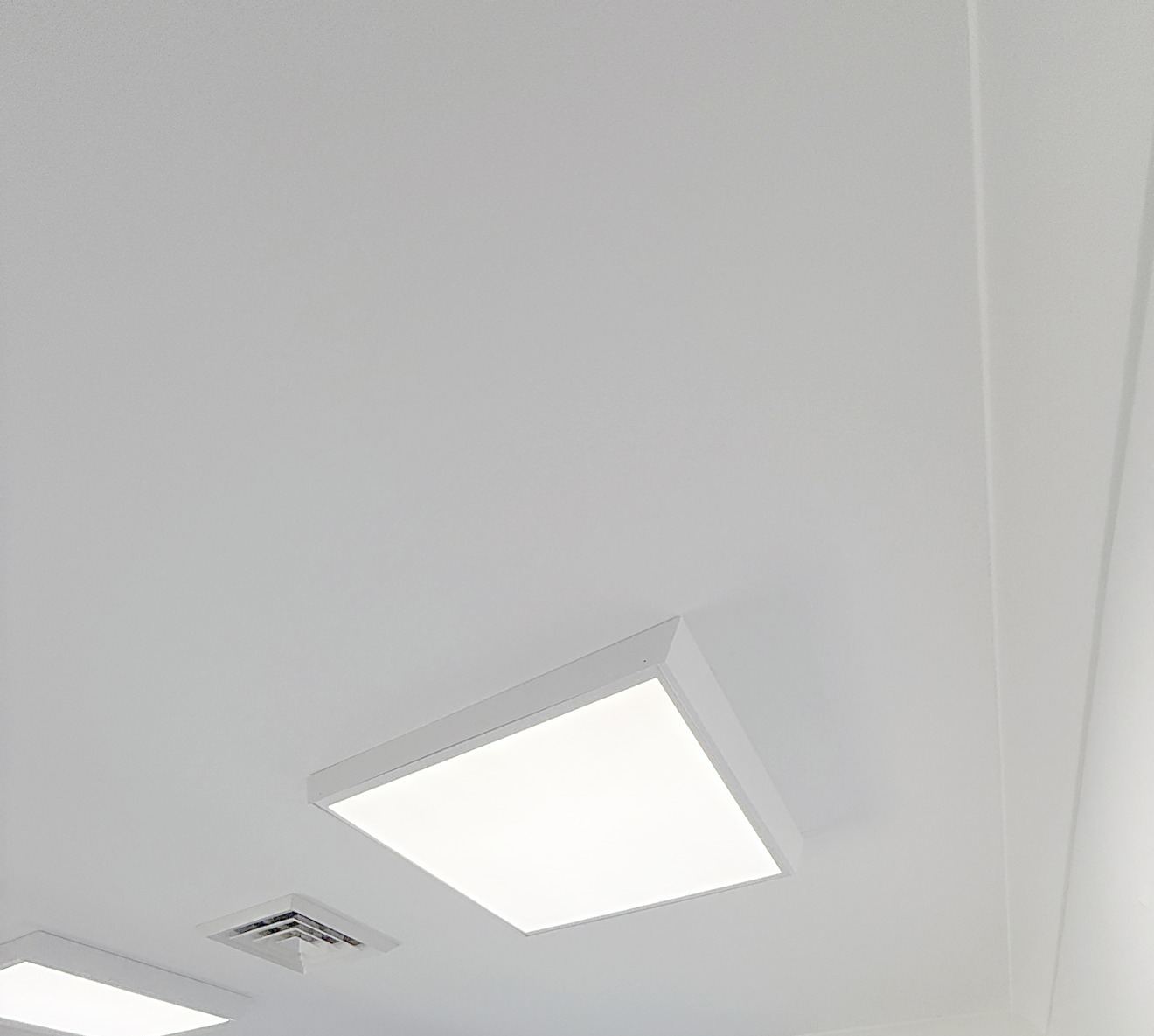 Square LED panel lights on a white office ceiling