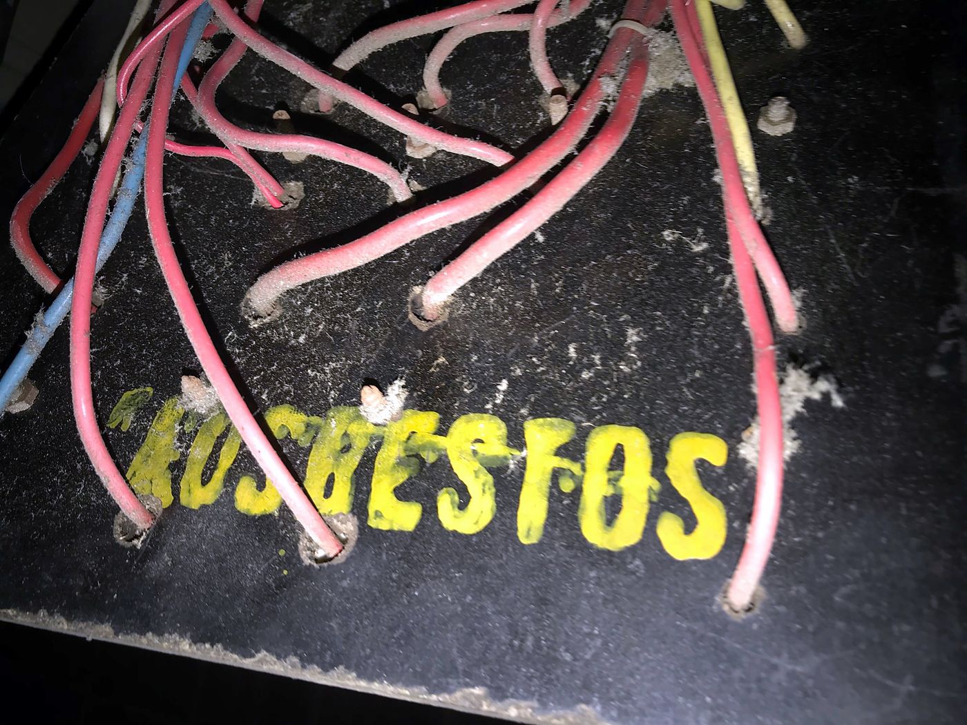 ASBESTOS stamped in yellow on the back of an old switchboard panel