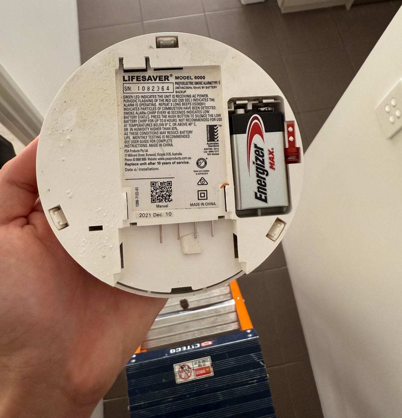 Checking the manufacture date on the back of a hard-wired smoke alarm