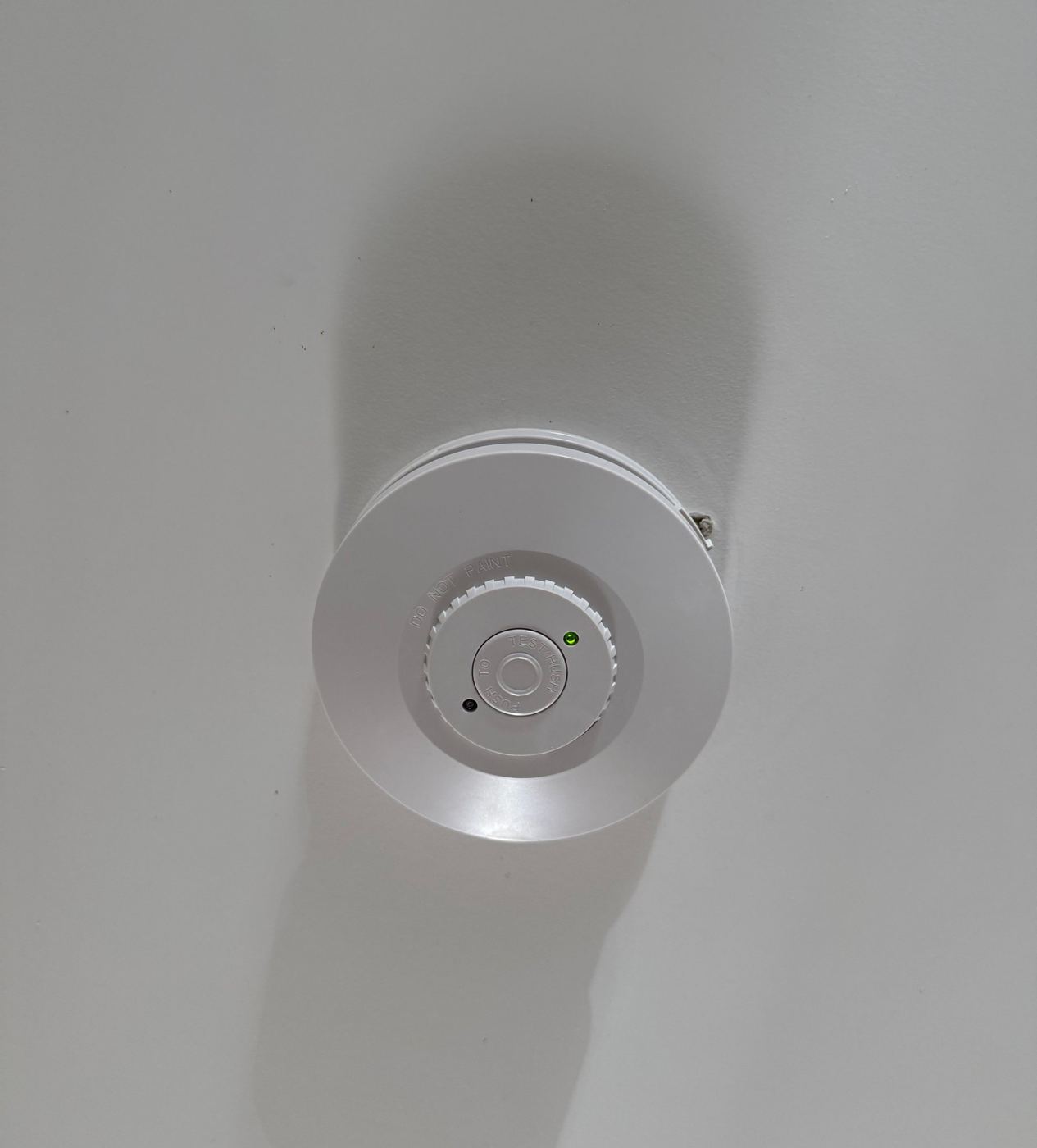 New hard-wired photoelectric smoke alarm installed on a ceiling